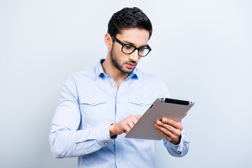 Portrait of busy man in blue shirt using wi-fi internet having tablet in hands texting massage checking email isolated on grey background, technology electronic wireless devices concept