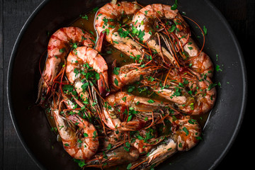 Shrimps fried in a pan. Classic recipe - parsley, garlic, chilli peppers and white wine.