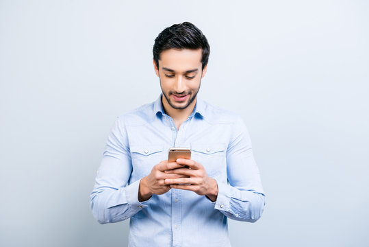 Portrait of cheerful man chatting with girlfriend, using 3G, wi-fi internet, having, smart phone cellphone in hands, surfing, isolated on grey background, technology concept