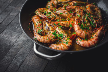 Shrimps fried in a pan. Classic recipe - parsley, garlic, chilli peppers and white wine.