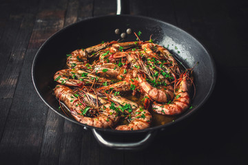 Shrimps fried in a pan. Classic recipe - parsley, garlic, chilli peppers and white wine.
