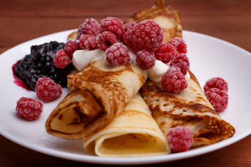 tasty home made pancakes with ice cream on craft wood table decorated with jam, raspberries and nuts