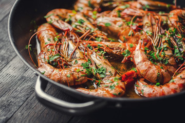 Shrimps fried in a pan. Classic recipe - parsley, garlic, chilli peppers and white wine.