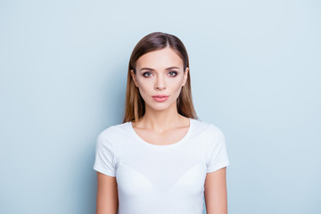 Obraz premium Portrait of pretty charming girl in white t-shirt with serious expression looking at camera isolated on grey background