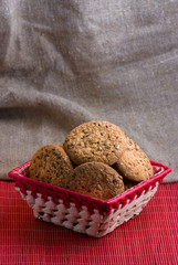 homemade oat cookies with sunflower seeds in and near red checkered basket on black wooden table