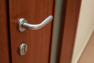 Obraz premium Silvery door handle and lock on the brown wooden door