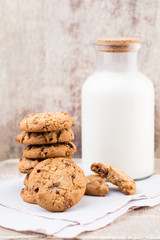 Chocolate oatmeal chip cookies with milk on the rustic wooden table.