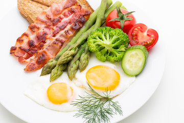 Fried eggs with bacon on the wooden table.