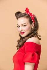 Beautiful young woman with pinup make-up and hairstyle. Studio shot on pastel background