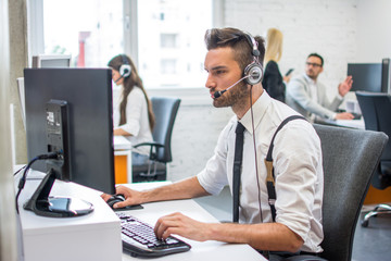 Beautiful handsome man with headset working in call center.