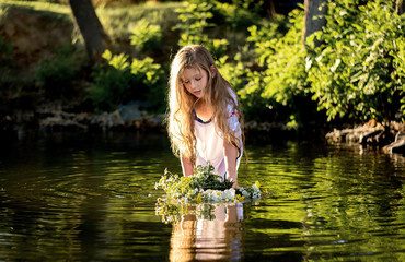 little girl with a wreath in a white dress in the water