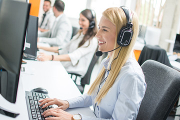 Beautiful blonde woman telephone operator talking with customer in call center