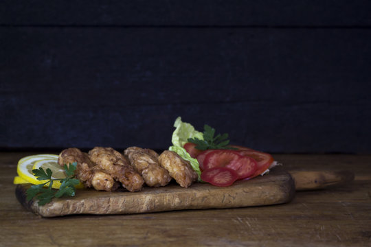 Breaded Chicken Meat With Salad And Lemon Resting On a Rustic Wooden Board