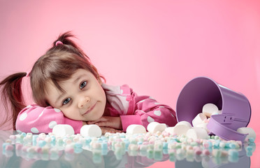 Portrait of a cute little girl with marshmallow on pink background.