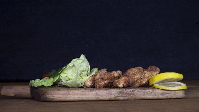 Breaded Chicken Meat With Salad And Lemon Resting On a Rustic Wooden Board