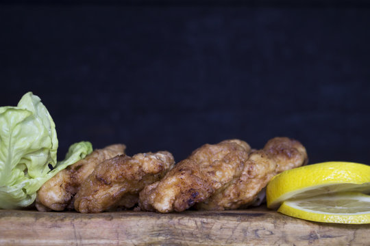 Breaded Chicken Meat With Salad And Lemon Resting On a Rustic Wooden Board