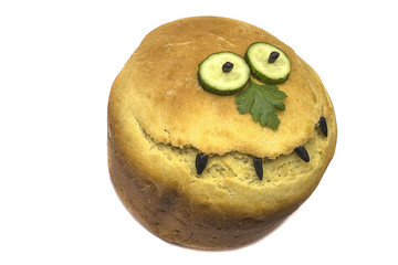 one loaf of bread with a crust in the form of a smile, eyes of a cucumber and a nose of parsley, isolated on a white background