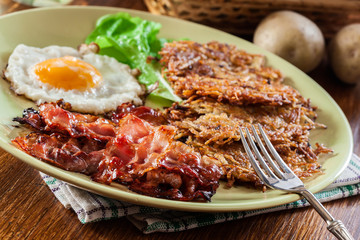 Hash browns. Potato pancakes with crispy fried bacon and fried egg