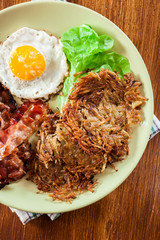 Hash browns. Potato pancakes with crispy fried bacon and fried e