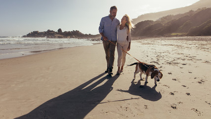 Couple walking a dog on the beach - Powered by Adobe