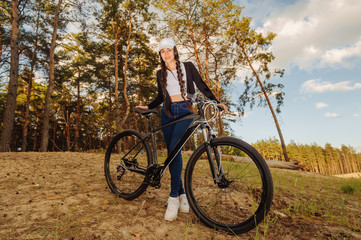 Fototapeta na wymiar Sport girl with a bike enjoys the view of sunset over an autumn forest. Heathy lifestyle concept