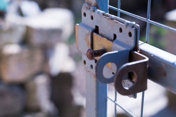 Opened old gray metal door with grid and bolt on sunny day