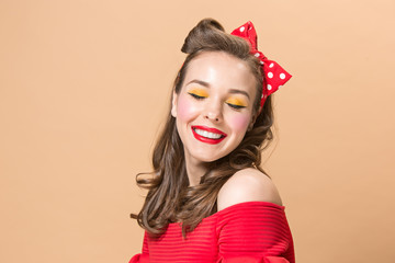 Beautiful young woman with pinup make-up and hairstyle. Studio shot on pastel background