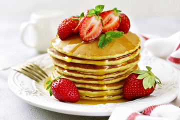 Stack of delicious pancakes with maple syrup and fresh strawberry for a breakfast.