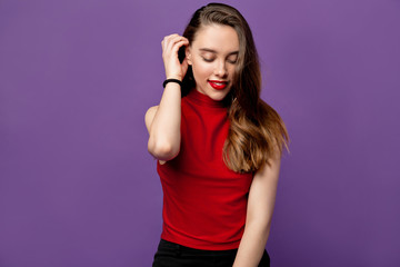 Close up Portrait of young adorable  charming attractive brunette girl smiling with shy view and fixes her hairstyle. Isolated on purple pastel Background. Copy space.