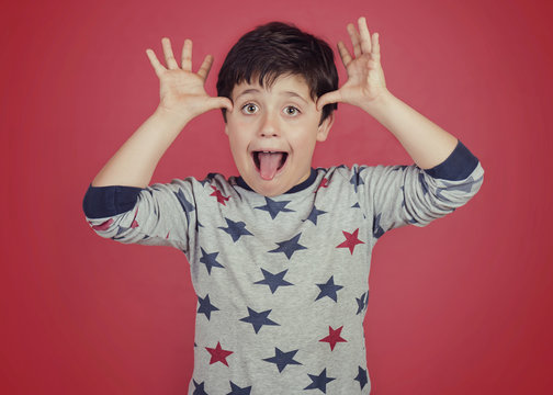 ni&ntilde;o gracioso que saca la lengua sobre fondo rojo