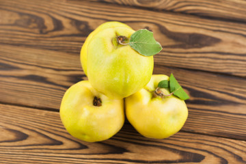Heap of whole fresh ripe quinces on old weathered rustic brown wooden table