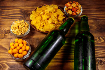 Bottles of beer and various snacks for beer on wooden table