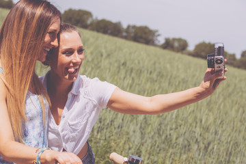 zwei junge frauen machen mit einer retro kamera fotos