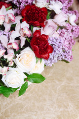 Bouquet of lilacs and red peonies on marble table