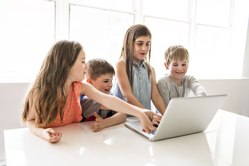Group of curious children watching stuff on the laptop screen
