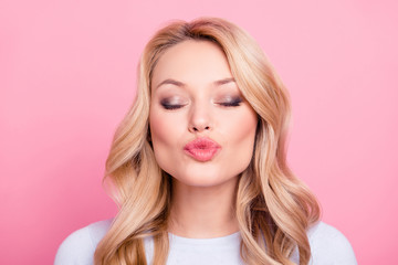 Portrait of lovely sweet girl in casual outfit with modern hairdo sending blowing kiss to the camera with close eyes isolated on pink background. Affection feelings concept