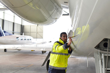 Aircraft mechanic inspects and checks the technology of a jet in a hangar at the airport