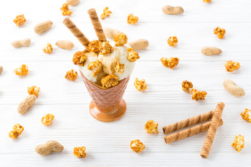 Ice cream with caramel and popcorn on a white table.