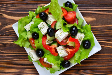 Greek salad on a wooden background. Space for text or design.