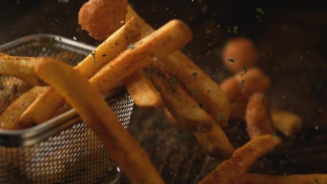 Camera follows french fries falling on wooden table. Shot with high speed camera, phantom flex 4K. Slow Motion.