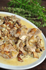 Tenderloin with mushrooms on a white platter. Tenderloin in cream sauce