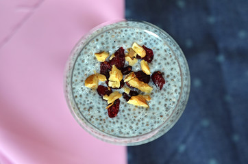 Chia pudding with raisins and nuts on pink and blue background