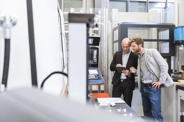 Two businessmen with tablet talking in modern factory