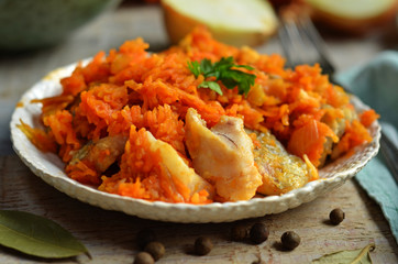 Fried fish with grated carrot on a white rustic plate