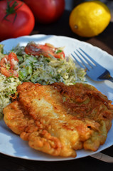 Fried fish in dough with salad on a white plate