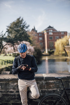 Senior man with cycling helmet using smartphone