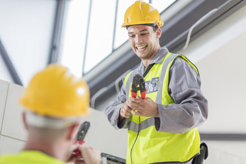 Two happy electricians working with wire stripper