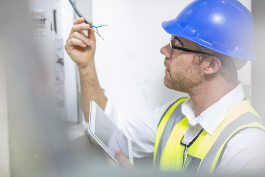 Electrician inspecting wire at fuse box