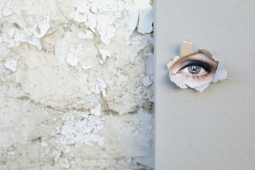 Book with eye looking through the cover leaning against weathered wall