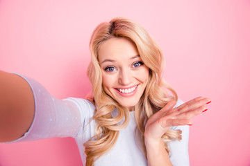 Self portrait of carefree funky girl in sweater shooting selfie on front camera gesturing with palm isolated on pink background. Free time weekend vacation concept